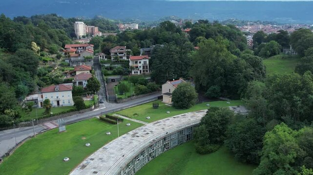 Talponia, the semi-subterranean residential unit in Ivrea, Piedmont, designed by Gabetti Isola in 1968, set in a curved green park at the city forest edge, drone shot slow motion