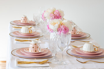 Elegant wedding table setting with pink peonies, gold cutlery, and crystal glassware, creating a romantic and sophisticated atmosphere.