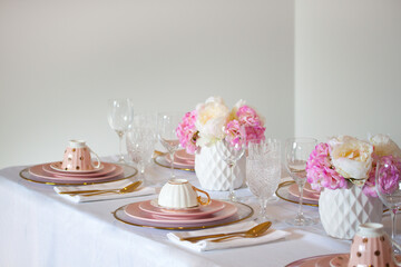 Elegant wedding table setting with pink peonies, gold cutlery, and crystal glassware, creating a romantic and sophisticated atmosphere.