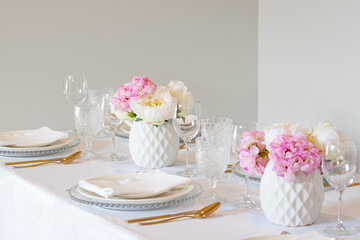 Elegant wedding table setting with pink peonies, gold cutlery, and crystal glassware, creating a romantic and sophisticated atmosphere.