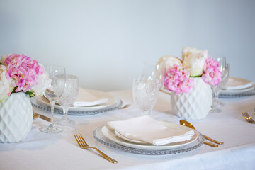 Elegant wedding table setting with pink peonies, gold cutlery, and crystal glassware, creating a romantic and sophisticated atmosphere.