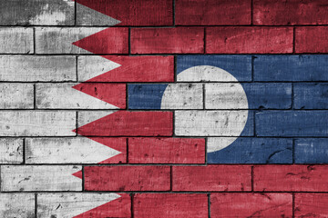 colourful painted big national flag of laos and flag of bahrain on a massive old brick wall background. concept