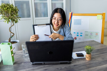 Young Thai Woman Showing Documents on Paper During Business Video Call from Home