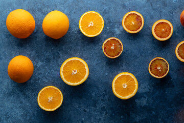 Fresh oranges and blood oranges lying on dark blue background