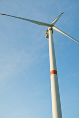 A windmill producing renewable energy against a blue sky on a beautiful spring day. Alternative renewable energy. Caring for the environment and climate change.