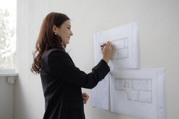 Designer architect reviewing building plans in modern office setting during daylight hours