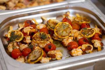Grilled shrimp skewers with lemon and tomatoes garnished with herbs
