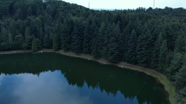 Drone slow motion shot of Meugliano Lake surrounded by alpine conifers in Valchiusella near Brosso, Piedmont, within the Ivrea Morainic Amphitheatre, a unique glacial geological formation, drone shot