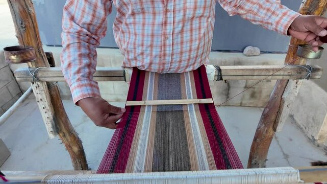 Weaver's hands making a striped textile with llama wool in Argentina.