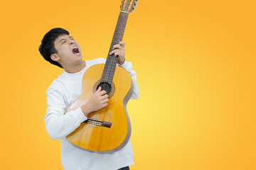 Young Man Joyfully Playing Guitar Against a Vibrant Yellow Background