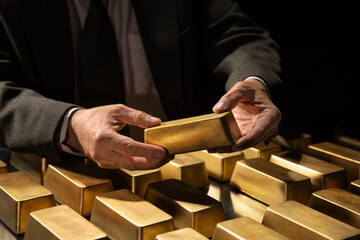 Hands of a banker or businessman, bank vault manager holding a gold bar, gold holdings concept. Savings and investments, business and finance