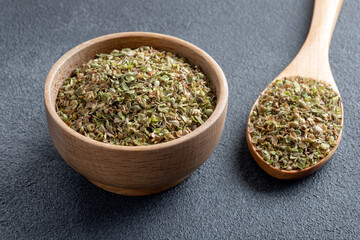 A bowl full of dried and ground natural mountain thyme on anthracite background
