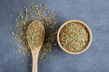 A bowl full of dried and ground natural mountain thyme on anthracite background