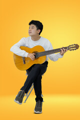 man sitting with acoustic guitar on a colorful orange background