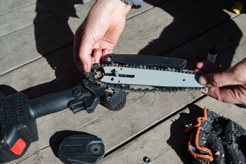 A man repairs an electric saw. Lubrication of the chain.