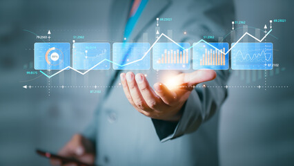 Businessman hand holding rising bar chart with glowing arrows, representing business growth, success, investment and data analytics in modern digital economy.