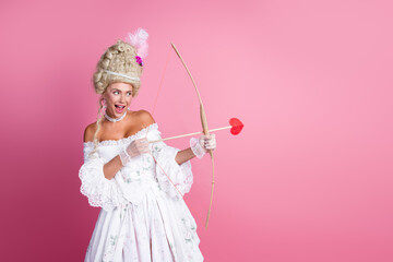 Elegant young woman dressed in vintage baroque style costume posing with a playful attitude against...