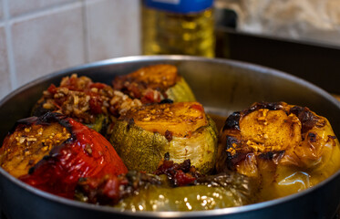 Photo shows stuffed peppers and tomatoes with rice inside a pan. Greek traditional plate mostly cooked at summertime.