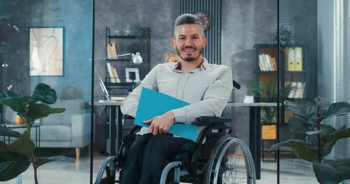 Portrait of a man in a wheelchair looking at the camera with a smile after a successful job interview. The concept of the employment of people with disabilities.