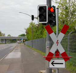 Roadside post with traffic light and electrified railway crossing sign on the left, symbolizing...