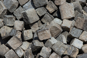 Scattered large gray granite cubes, cut into uniform blocks, lying randomly on the ground. Abstract...