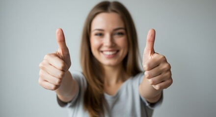 Young woman gives approving thumbs up against plain backdrop, for advertisement