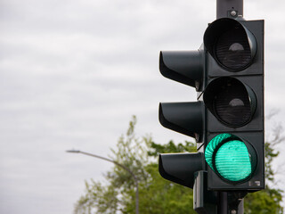 Black traffic light with a bright green signal illuminated, symbolizing go-ahead, urban transportation control, and safe road navigation.
