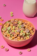 Colorful breakfast cereal with milk on pink background. Fun snack 