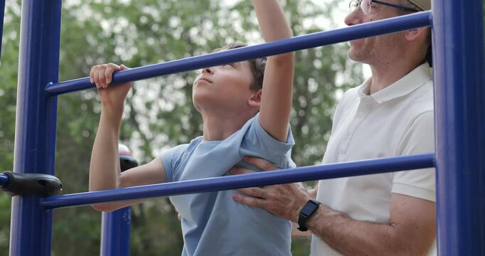 Happy child climbs stairs with father support in outdoor park. Child shows courage while father offers support. Scene of happy child and parenting bond reflects growth, support, and trust.