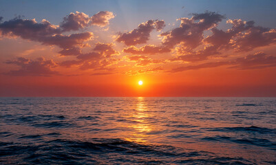 Fototapeta premium Vibrant sunset over the ocean with golden and orange hues reflecting on gentle waves, creating a serene and tranquil coastal scene