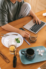  Gen Z woman working from home at cozy kitchen table with laptop and phone. Digital nomad lifestyle, mindfulness, remote work, balance, mental calm and modern freelancing