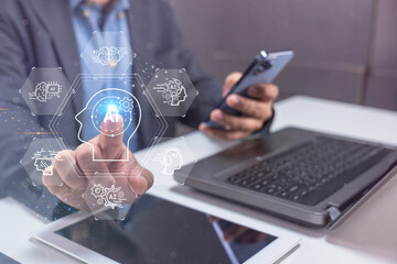 A person interacts with a virtual touchscreen interface displaying technology icons, working with a laptop, tablet, and smartphone.