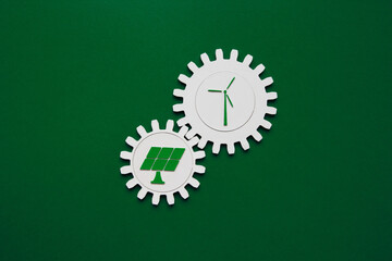 Interlocking gear wheels with wind turbine and solar panel icons on green background. Renewable...