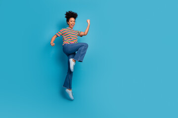 Happy young woman in a striped t-shirt strikes a joyful pose on a vibrant turquoise background...