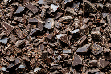 Pile broken dark chocolate bar on background, closeup, top view,. Sweet food