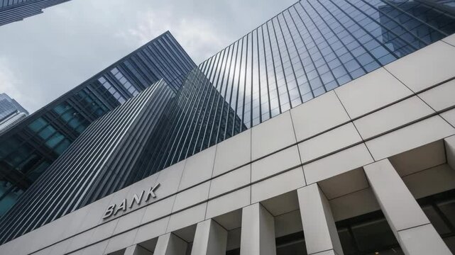 Modern bank building exterior with glass facade against cloudy sky. Finance concept.