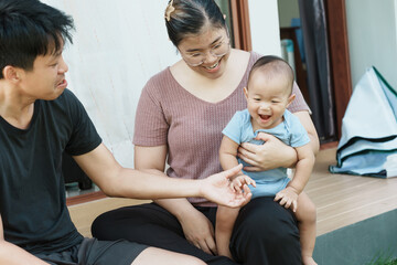 At home, a baby plays with their parents and aunt, sharing moments of laughter and occasional tears. The lively atmosphere reflects the warmth, joy, and emotional ups and downs of family life.
