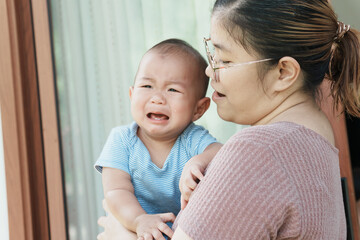At home, a baby plays with their parents and aunt, sharing moments of laughter and occasional tears. The lively atmosphere reflects the warmth, joy, and emotional ups and downs of family life.
