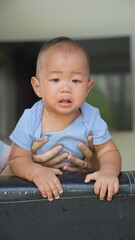 At home, a baby plays with their parents and aunt, sharing moments of laughter and occasional tears. The lively atmosphere reflects the warmth, joy, and emotional ups and downs of family life.
