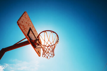 Low-angle shot of a weathered basketball hoop with a rusty pole and worn net, silhouetted against a vibrant clear sky—ai generative.