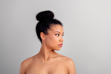 Obraz premium Elegant young woman with stylish bun hairstyle posing against a white background, showcasing natural beauty