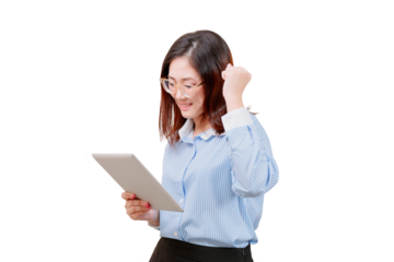 Asian young beautiful woman wearing glasses smiles while looking at a tablet and raising her fist in a gesture of excitement.