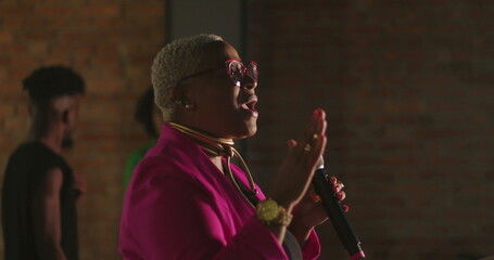 African descent woman delivering emotional sermon during evangelical church gathering, holding...