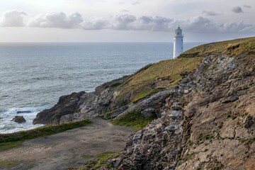 Scenic coastal lighthouse on rocky cliff.