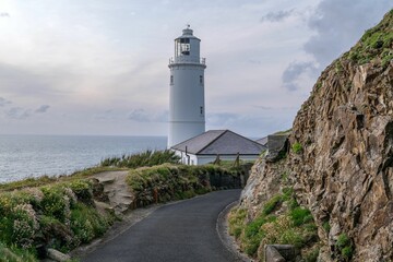 Scenic lighthouse by the sea with rocky path.