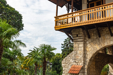 Large elegant stone balconies of an old historical building. Fine stonework of large stones. View of the garden with tall palm trees