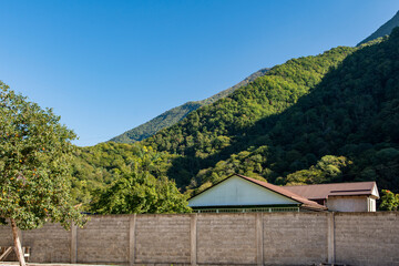 Impressive view of high mountain peaks covered with green dense forest. Warm autumn day