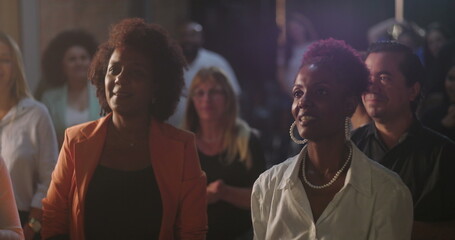 Group of women smiling and standing in worship, diverse congregation expressing faith and joy, Christian spirituality in a church environment, community unity and praise