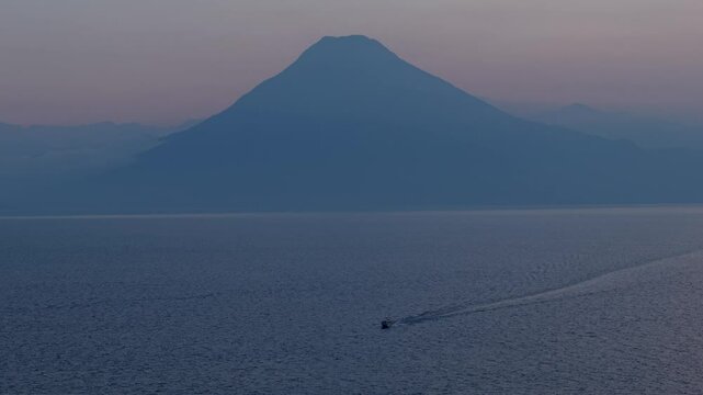 Cinematic aerial view over Lake Atitl&aacute;n revealing San Juan La Laguna's iconic piers, colorful boats, and the towering volcanoes that dominate the Guatemalan highlands
