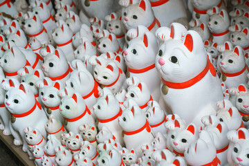 Tokyo, Japan - Sep 30 2024, A close-up view of many multi-sized white beckoning cat figure of Maneki neko with red ears and noses displayed at Gotokuji Temple, without people, at daytime, Tokyo, Japan